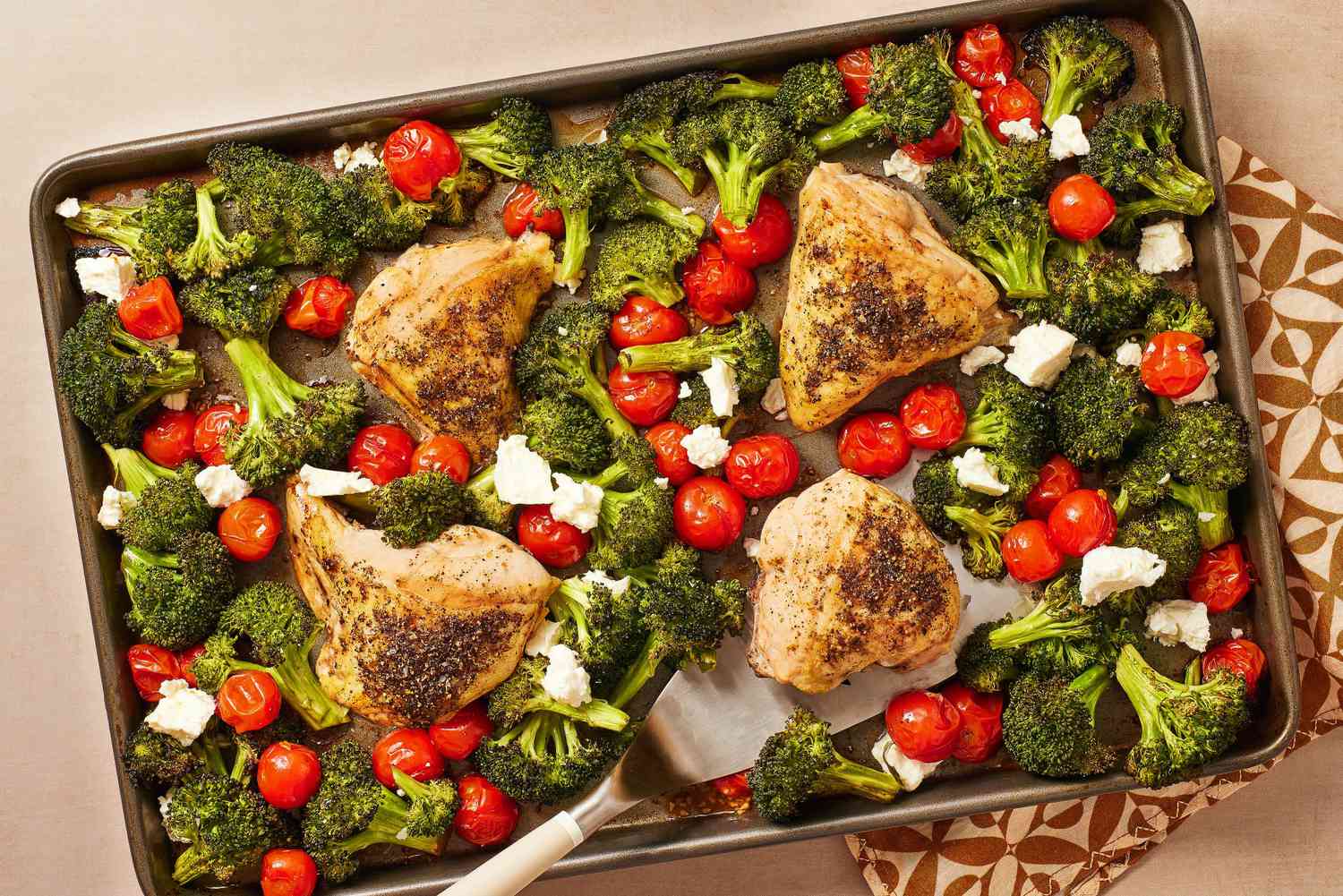 Prepared sheet pan dinner with chicken, broccoli, and tomatoes