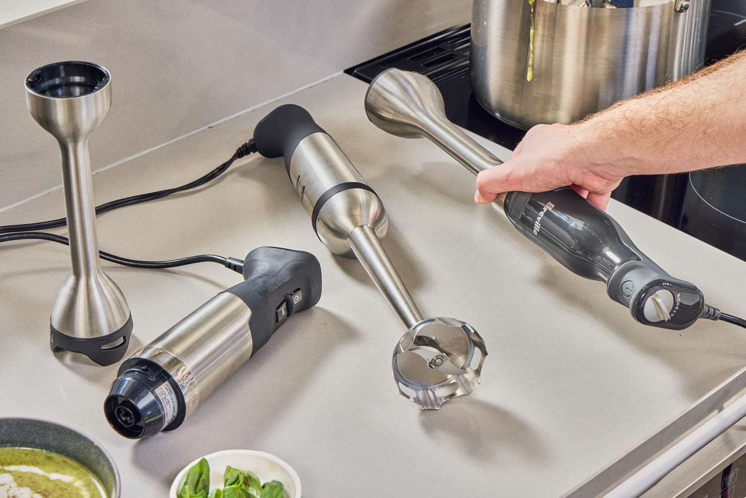 Multiple immersion blenders on a kitchen counter, with one being used