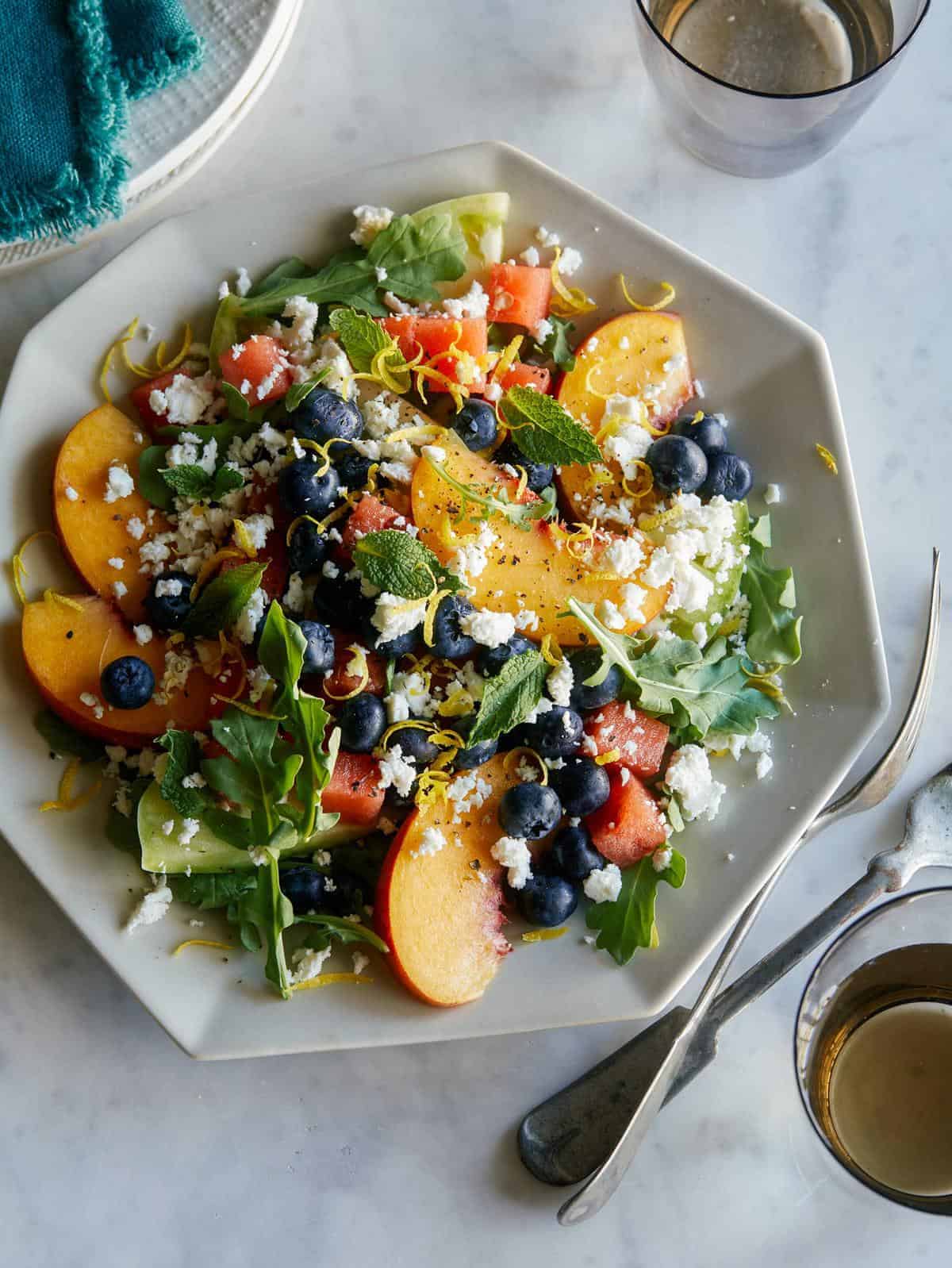Fresh salad containing peaches, tomatoes, and greens